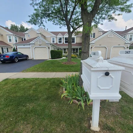 a front view of a house with a garden and trees