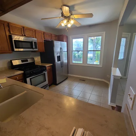 a kitchen with stainless steel appliances a stove a refrigerator a sink a microwave a dining table and chairs