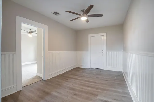 an empty room with wooden floor and a ceiling fan
