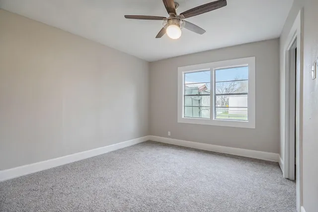 an empty room with a window and a fan