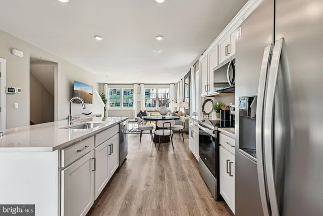 a kitchen with stainless steel appliances a refrigerator a stove a sink dishwasher a oven with white cabinets and wooden floor