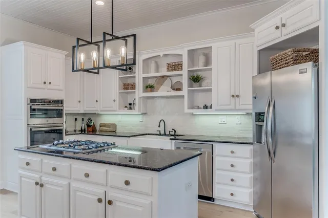 a kitchen with granite countertop stainless steel appliances a sink stove and refrigerator