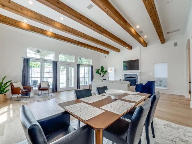 a view of a dining room and livingroom with furniture wooden floor a rug a flat screen tv a rug and a chandelier