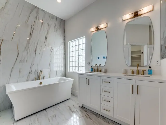a bathroom with a double vanity sink a mirror and a bathtub