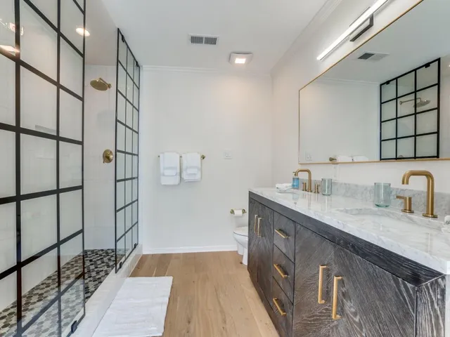 a spacious bathroom with a granite countertop sink a mirror and shower