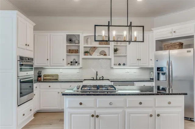 a kitchen with stainless steel appliances granite countertop a stove a refrigerator and a white cabinets