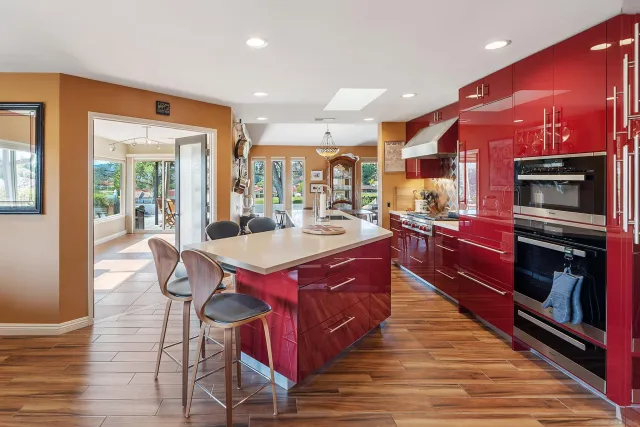 a open kitchen with stainless steel appliances kitchen island granite countertop a table chairs and a refrigerator
