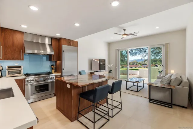 a kitchen with stainless steel appliances granite countertop a stove top oven a sink dishwasher a dining table and chairs with wooden floor