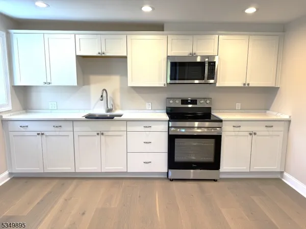 a kitchen with granite countertop a stove a sink and a microwave