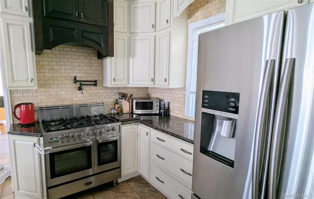 a kitchen with stainless steel appliances granite countertop white cabinets and white appliances
