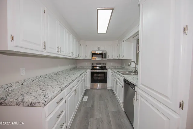 a kitchen with granite countertop white cabinets and stainless steel appliances