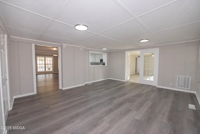 a view of an empty room with wooden floor and windows