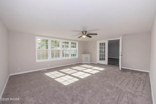 a view of an empty room with window and hardwood floor