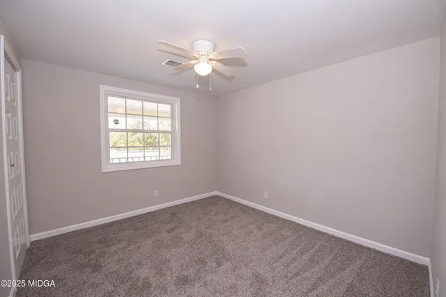 an empty room with windows and fan