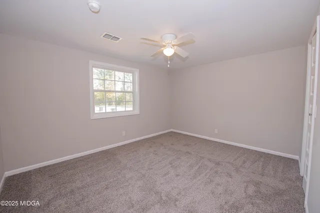 an empty room with windows and fan