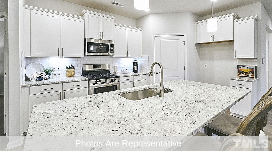 3635 Alcorn Ridge Trace Whitsett, NC 27377 - Photo 8 of 17 a kitchen with granite countertop a sink a stove and refrigerator