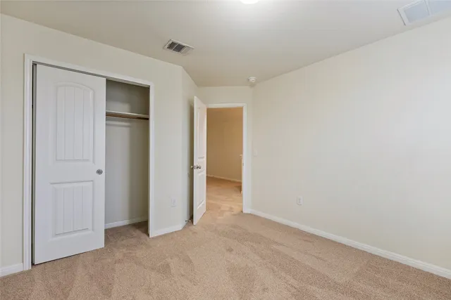 a view of an empty room with closet and wooden floor