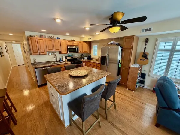 a kitchen with stainless steel appliances granite countertop a table chairs and a refrigerator