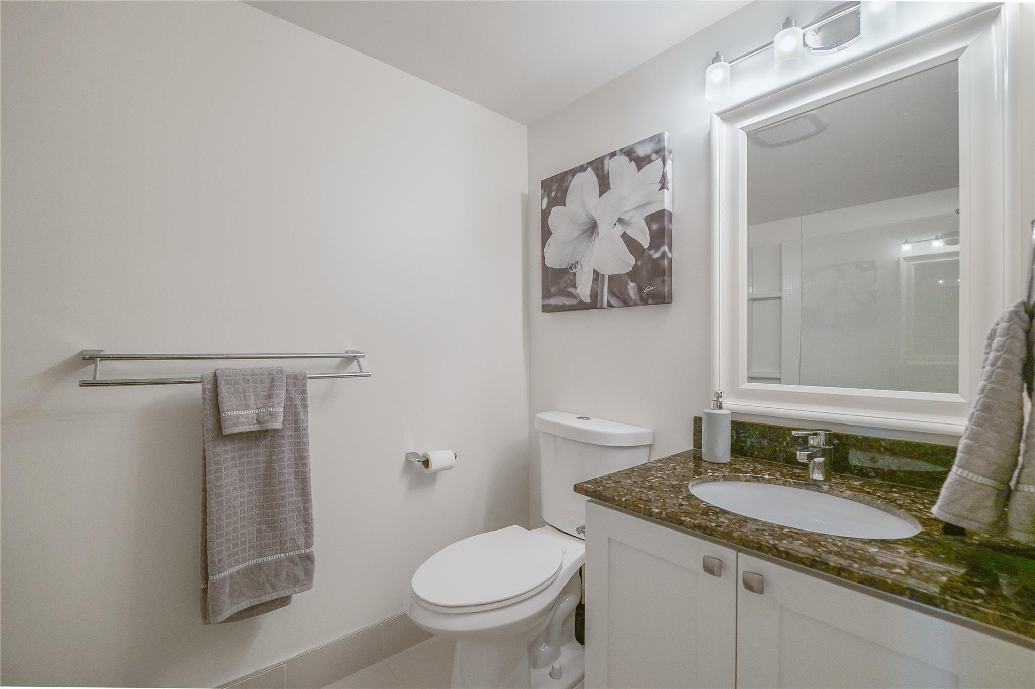 3930 Inverrary Boulevard, Unit 703D Lauderhill, FL 33319 - Photo 31 of 72 a bathroom with a granite countertop sink toilet and mirror