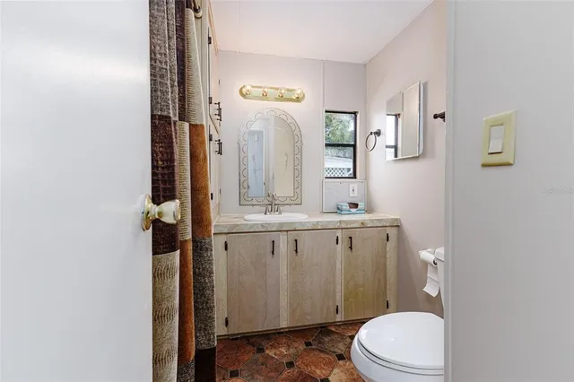 a bathroom with a granite countertop toilet sink and mirror