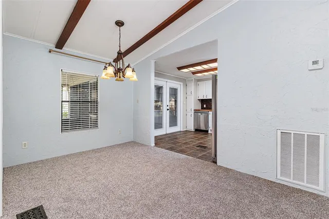 an empty room with chandelier fan and windows