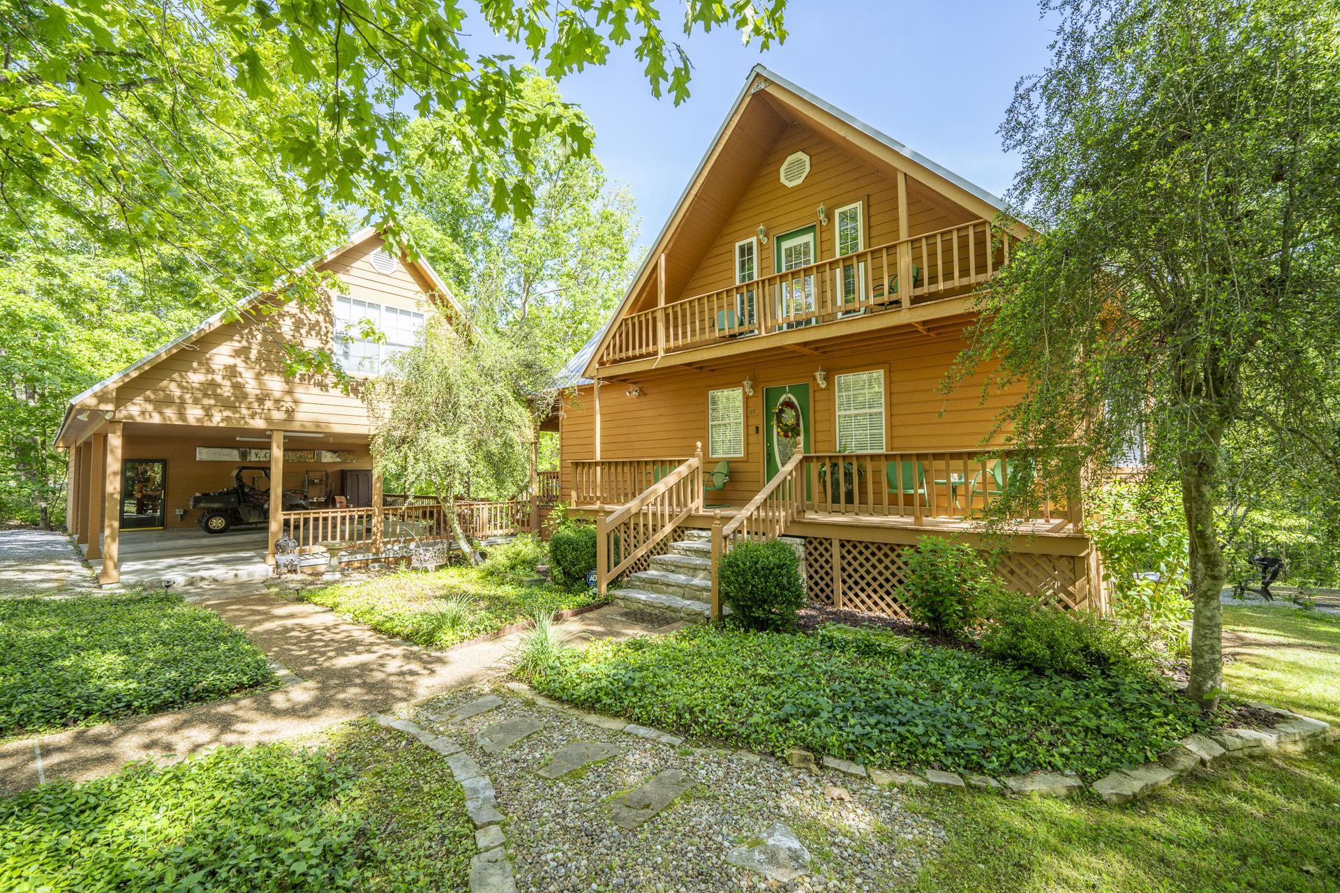 Wood-sided residence featuring a prominent balcony, a front porch with railing, and a stone pathway