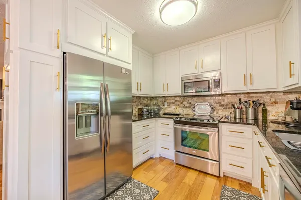 a kitchen with stainless steel appliances granite countertop a refrigerator sink and stove