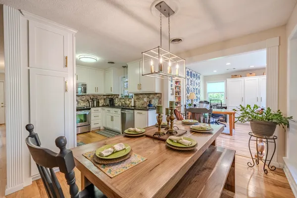 a view of a dining room and livingroom with furniture wooden floor a chandelier