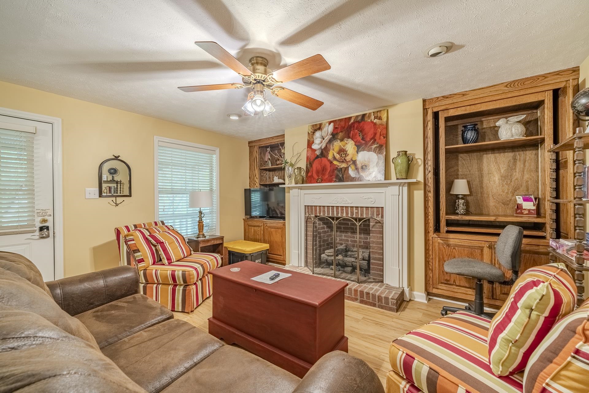 85 Cr 256 Road Iuka, MS 38852 - Photo 26 of 38 Living area featuring a brick fireplace with a white mantel, wood-finish flooring, and built-in wood shelving