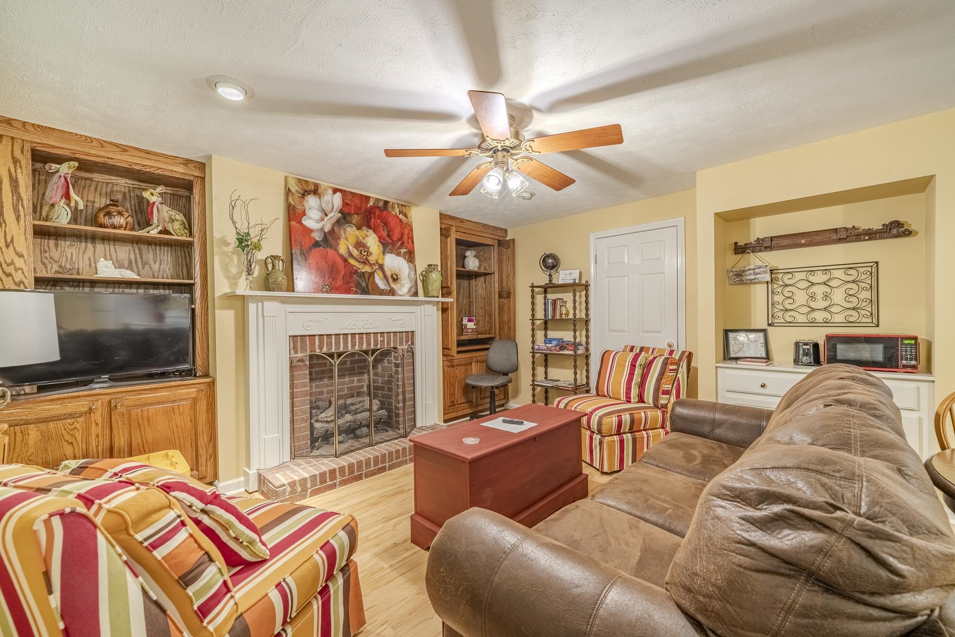 85 Cr 256 Road Iuka, MS 38852 - Photo 27 of 38 Living area featuring a brick fireplace with a white mantel, wood-finish flooring, recessed lighting, a ceiling fan, and built-in wood cabinetry