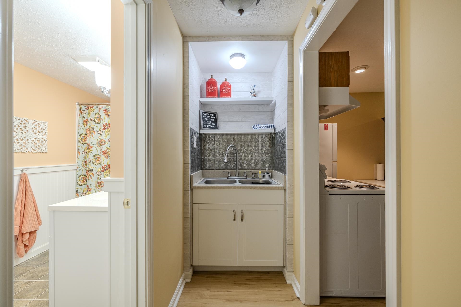 85 Cr 256 Road Iuka, MS 38852 - Photo 29 of 38 Compact utility area featuring a double basin sink, white cabinetry, decorative backsplash, and wood-finish flooring