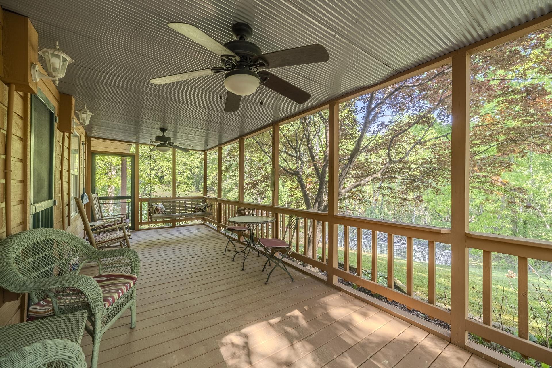 85 Cr 256 Road Iuka, MS 38852 - Photo 31 of 38 Screened porch featuring a corrugated metal ceiling, wood-finish flooring, and two ceiling fans with integrated lighting