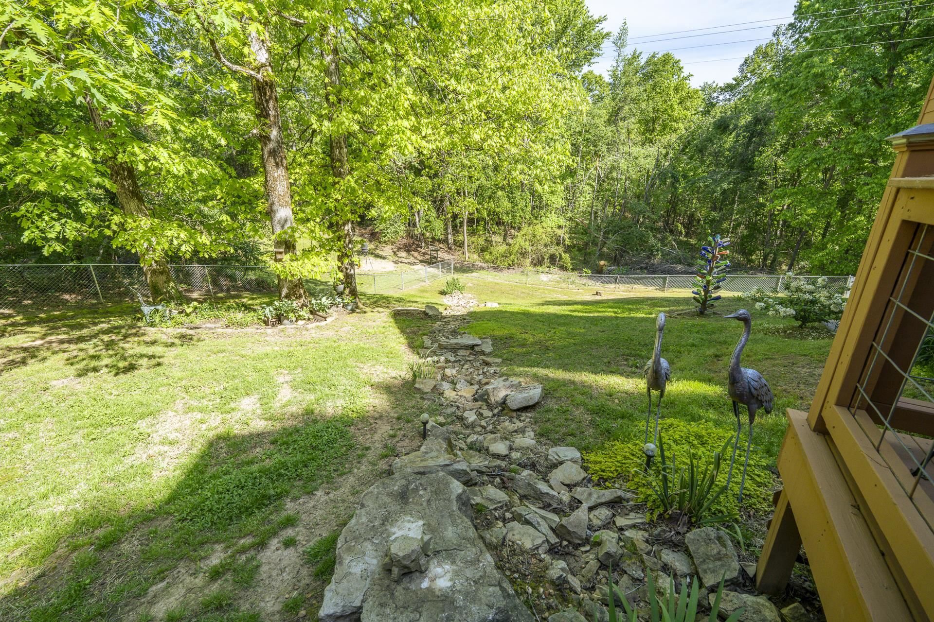 85 Cr 256 Road Iuka, MS 38852 - Photo 35 of 38 Expansive rear yard featuring a manicured lawn, established landscaping, mature trees, and a rock-lined dry creek bed