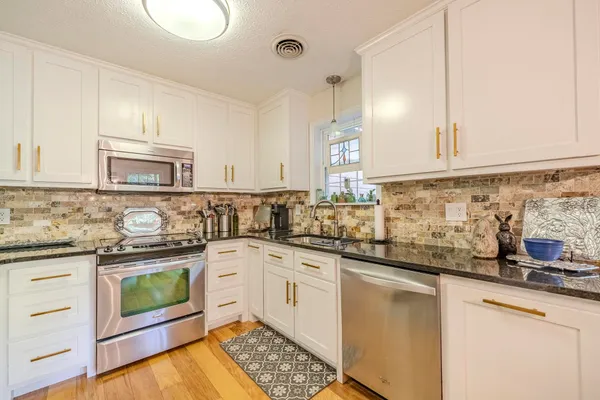 a kitchen with granite countertop white cabinets and white appliances