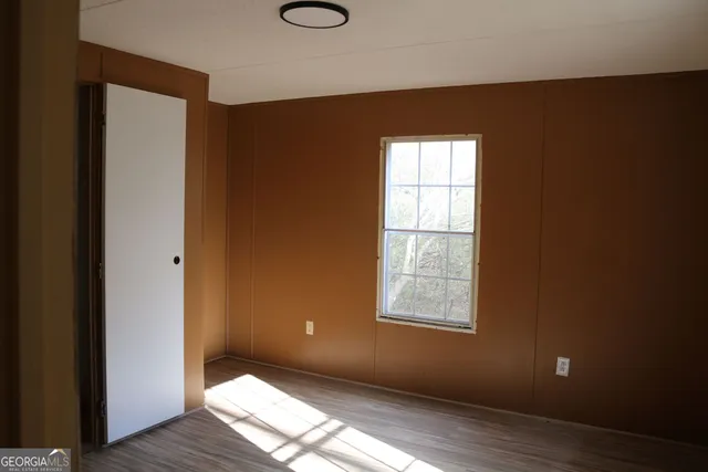 an empty room with wooden floor closet and windows
