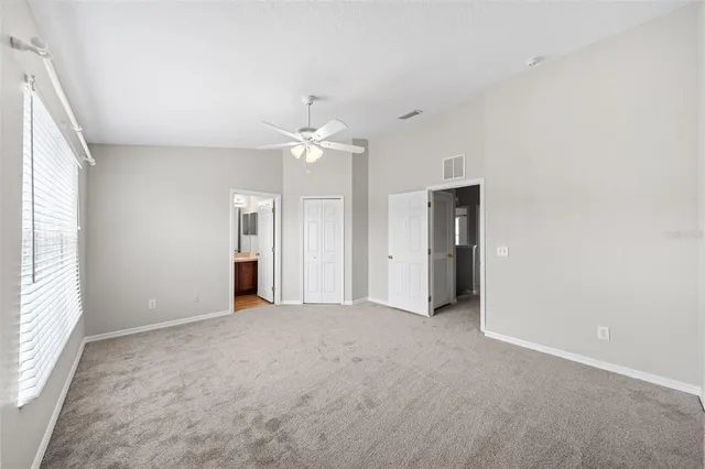 an empty room with windows and fan