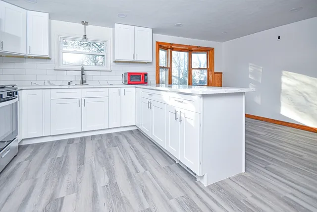 a kitchen with granite countertop white cabinets sink and window