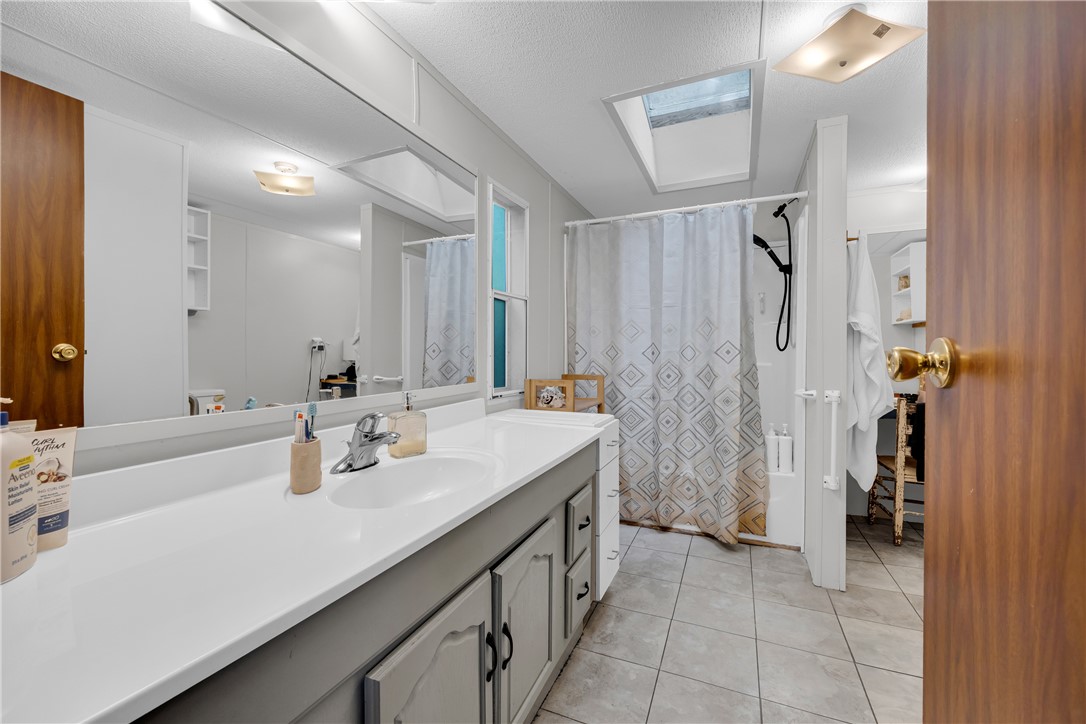 162 Newberry Road Walhalla, SC 29691 - Photo 19 of 50 A well-lit bathroom features a long vanity, tile flooring, and a shower with a skylight overhead.