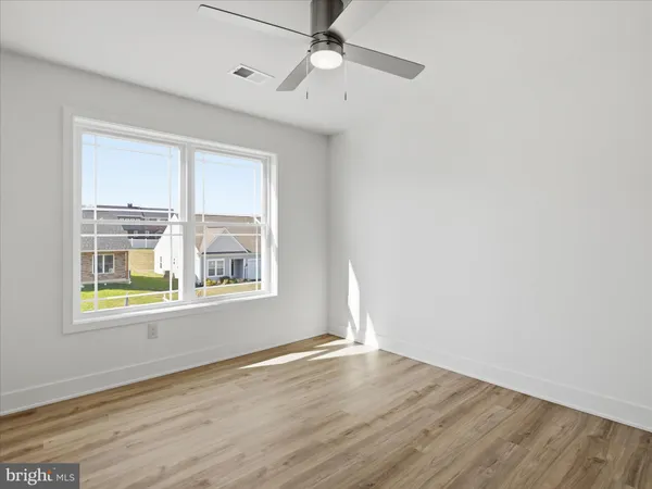 an empty room with wooden floor chandelier fan and windows