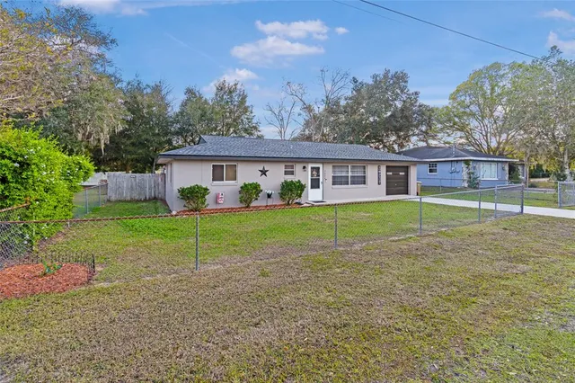 a view of house with a big yard and potted plants