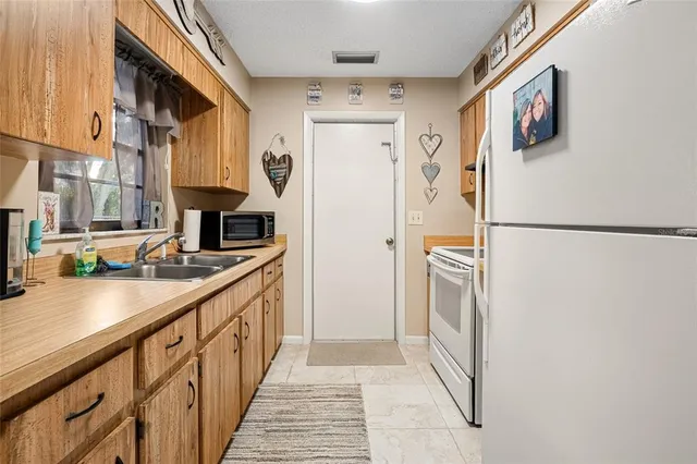 a kitchen with stainless steel appliances a refrigerator a sink and white cabinets