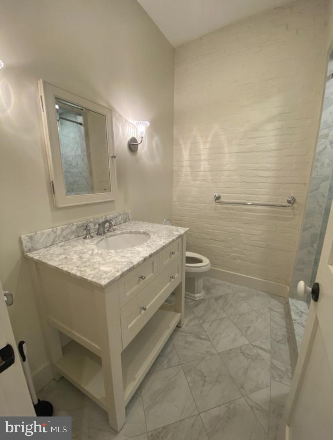 19 Branch Lane East Baltimore, MD 21202 - Photo 6 of 13 a bathroom with a granite countertop sink a toilet and a mirror