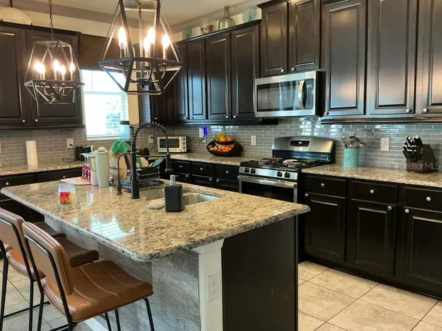 a kitchen with stainless steel appliances granite countertop a sink a stove and microwave