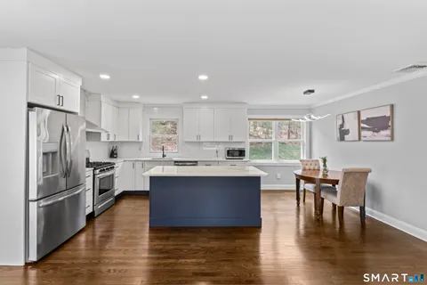 a kitchen with stainless steel appliances granite countertop a table chairs refrigerator and a stove