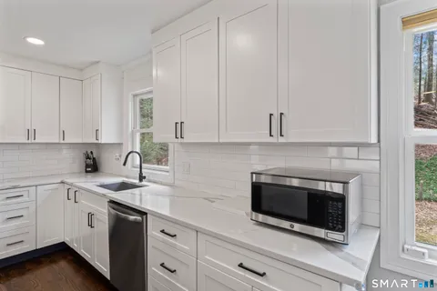 a kitchen with stainless steel appliances granite countertop white cabinets and a sink