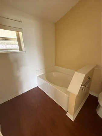 a view of a hallway with wooden floor and cabinet
