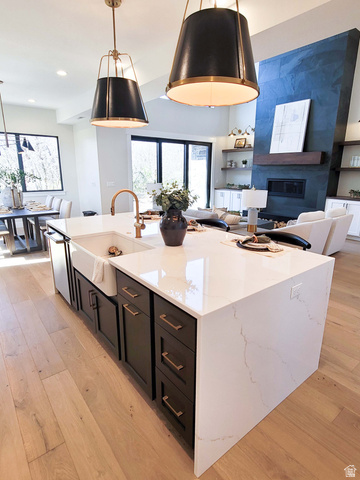 Kitchen island with a waterfall countertop, farmhouse sink, and bronze faucet
