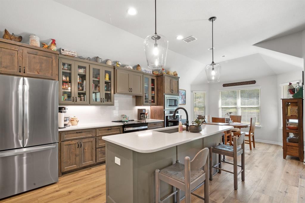 355 Sunset Cove Bluff Dale, TX 76433 - Photo 12 of 40 a kitchen with stainless steel appliances a table chairs wooden floors and a view of living room