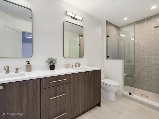 a bathroom with a toilet a sink a mirror and a shower