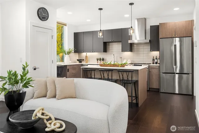 a living room with stainless steel appliances kitchen island a table chairs in it and a refrigerator